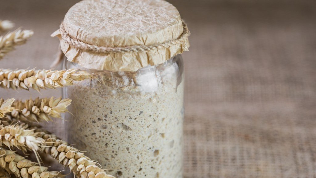 Levain naturel en pot, entouré d'épis de blé